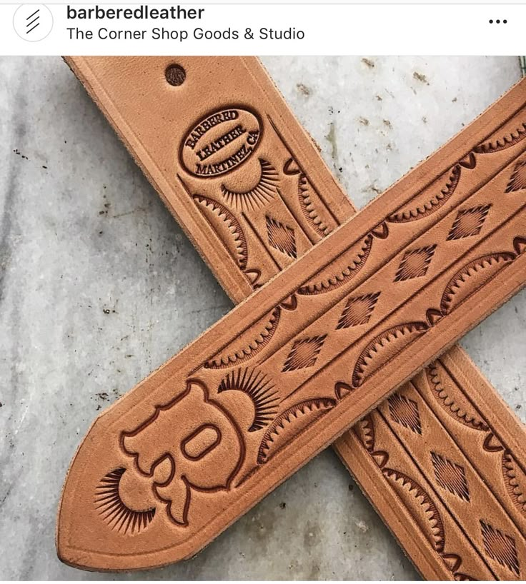 two leather straps with designs on them sitting next to each other in the shape of a cross