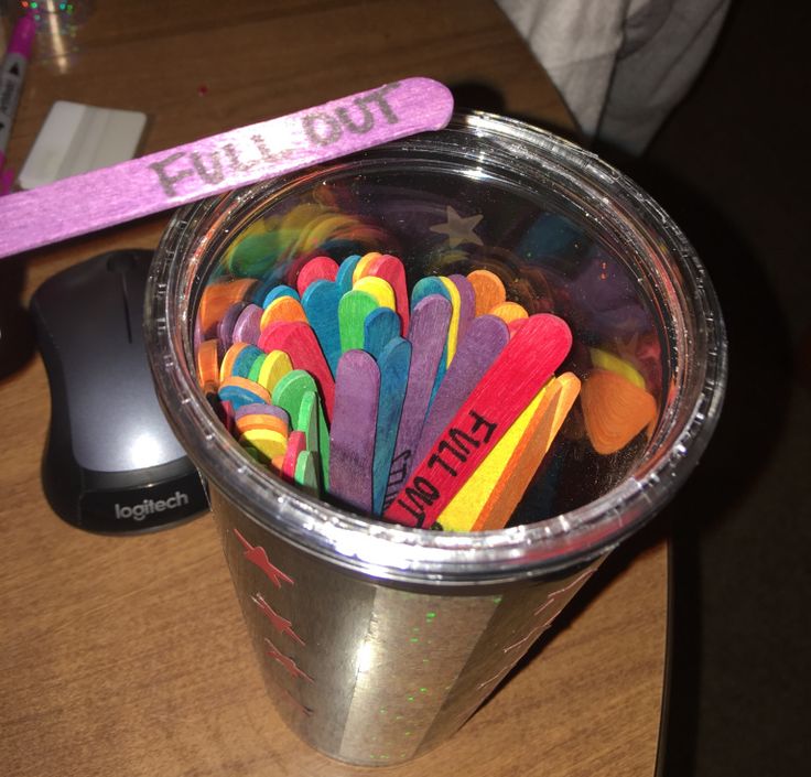 a cup filled with lots of different colored toothbrushes next to a computer mouse