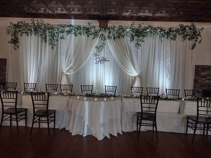 the tables are set up with white linens and greenery at the head table