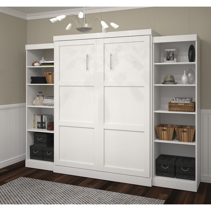 a white bookcase with two doors and baskets on the bottom shelf next to it