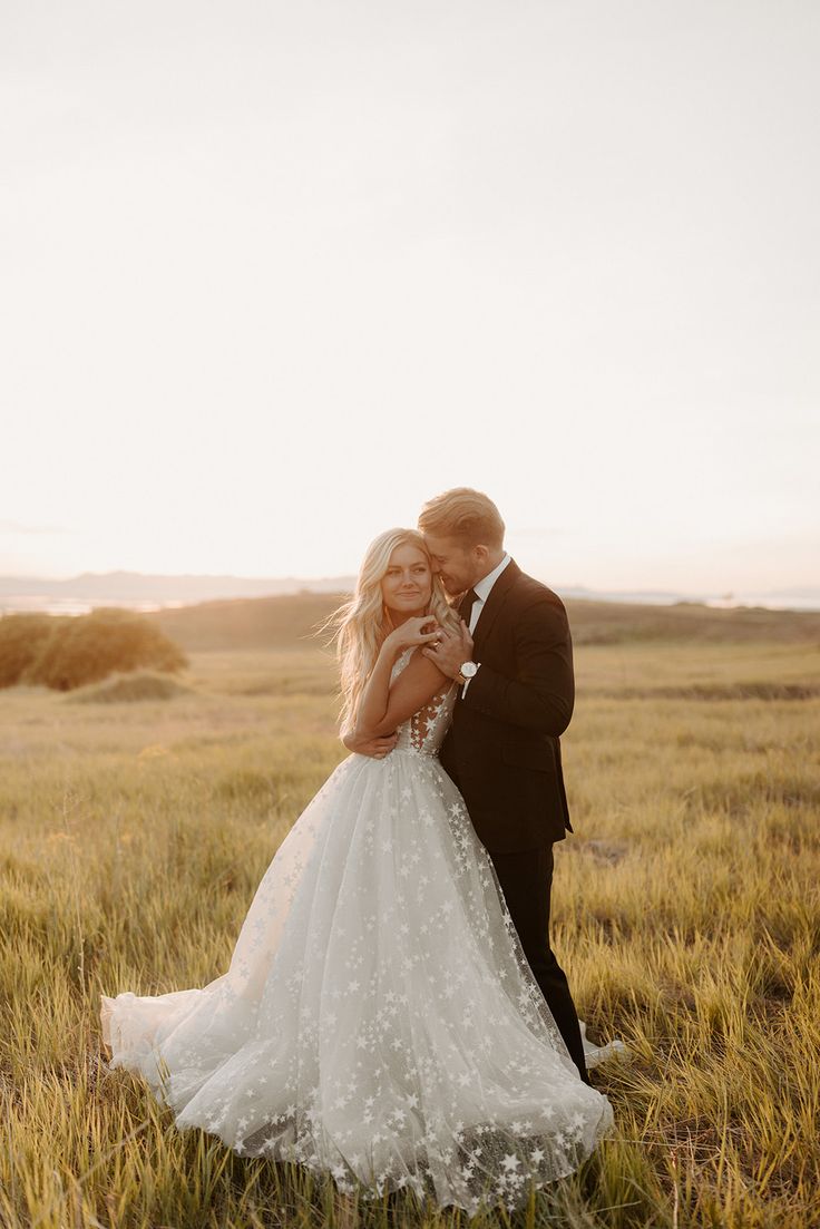 a bride and groom embracing in the middle of a field