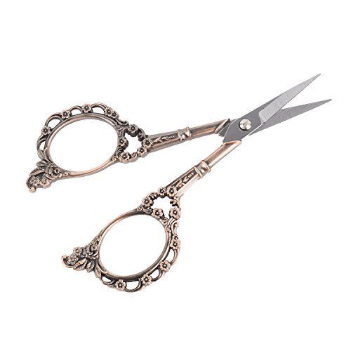 a pair of scissors with ornate designs on the handles and sides, both in silver