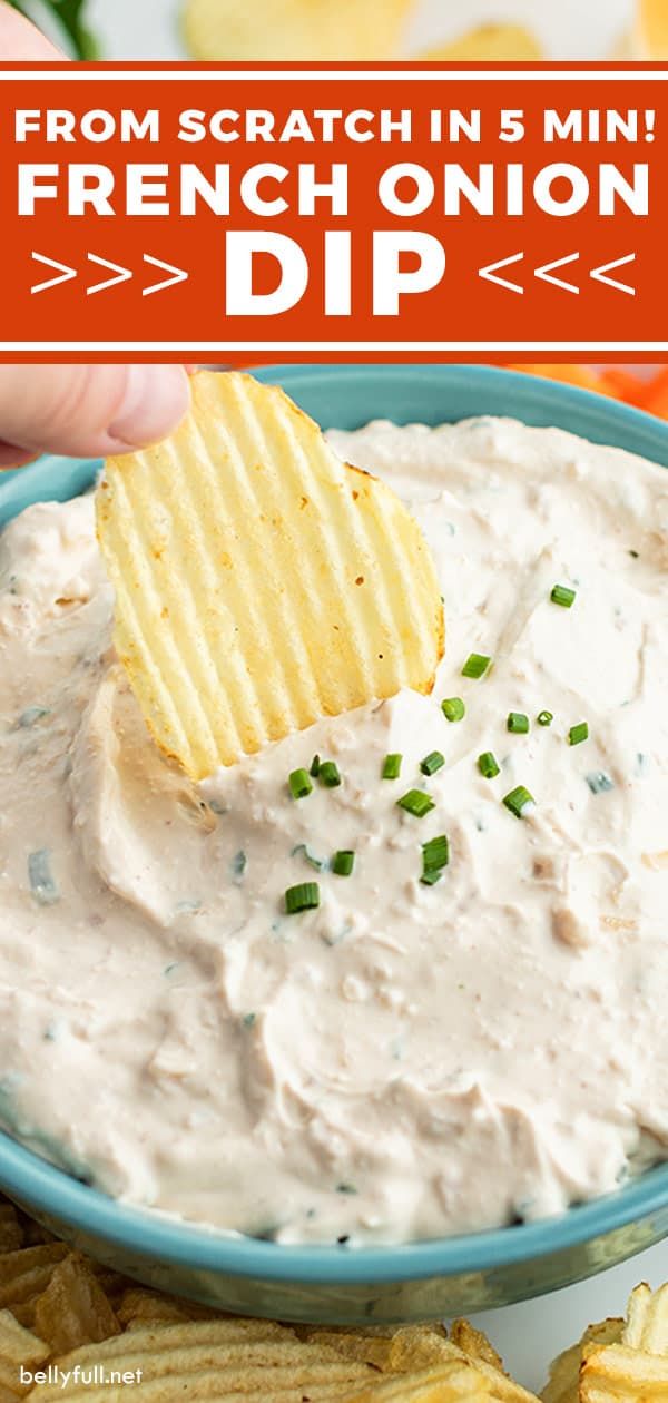 a hand dipping a cracker into a bowl of dip with chips on the side