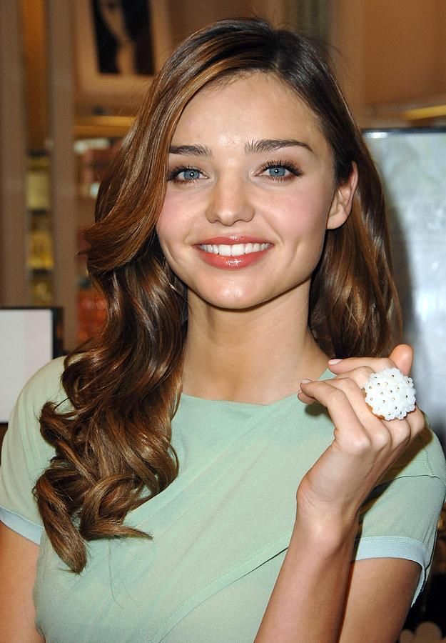 a beautiful young lady holding a white object in her hand and smiling at the camera