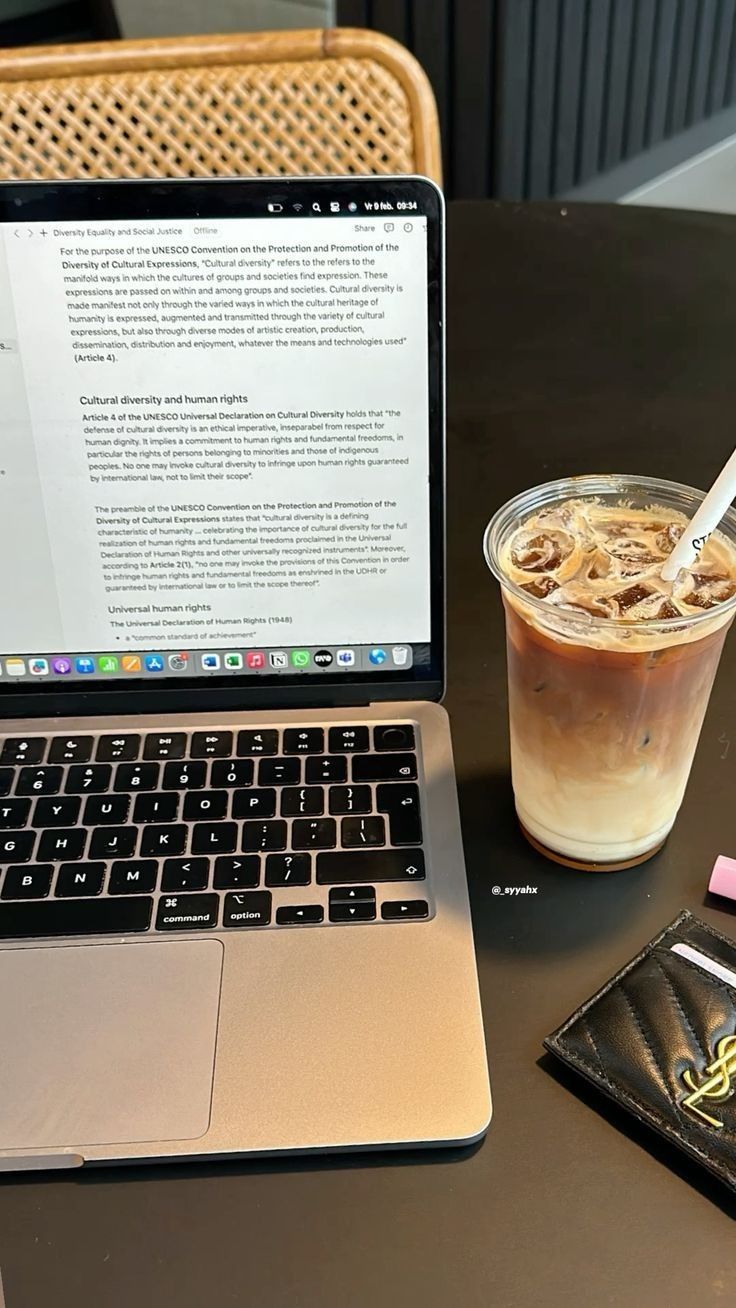 an open laptop computer sitting on top of a table next to a cup of coffee