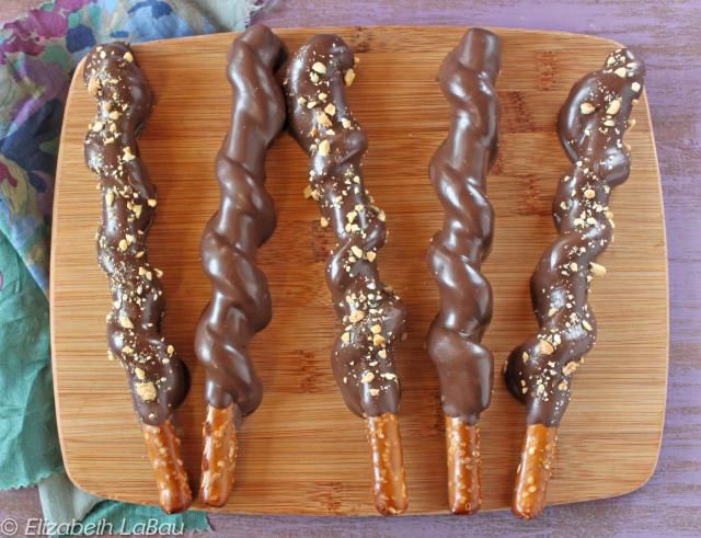 four chocolate covered donuts on a wooden platter