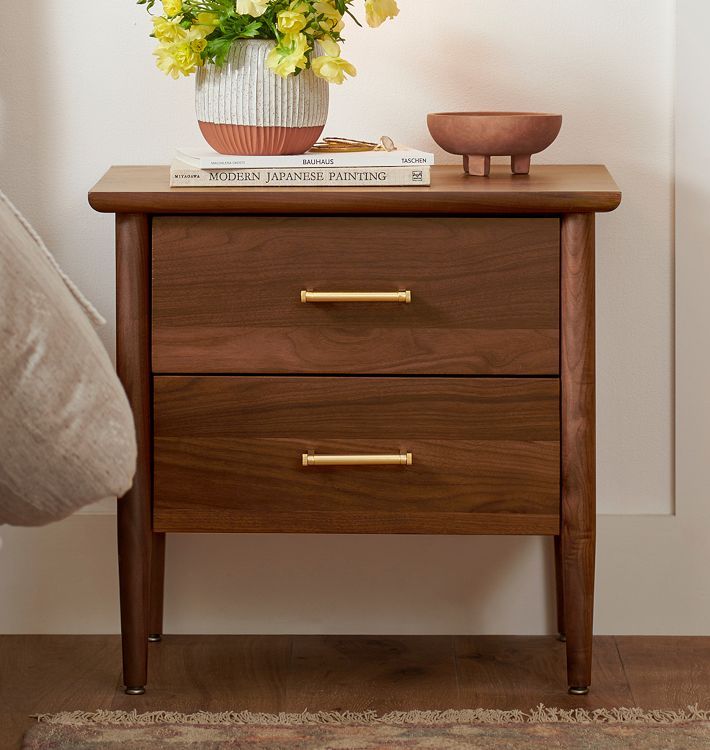 a nightstand with two drawers and a potted plant on the top shelf next to it