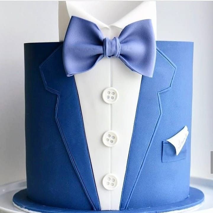 a blue and white cake decorated with a tuxedo, bow tie and button