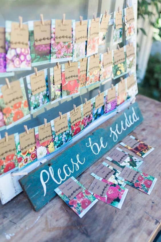 a wooden table topped with lots of flowers and notes attached to clothes pins that say please to send