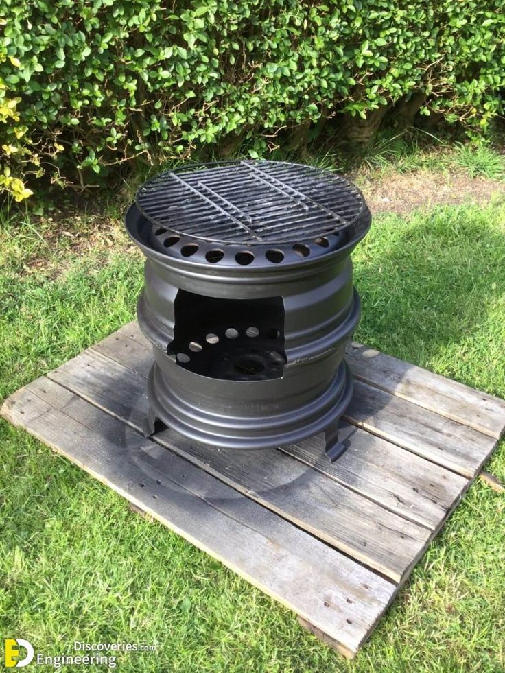 an outdoor bbq grill sitting on top of a wooden pallet in the grass