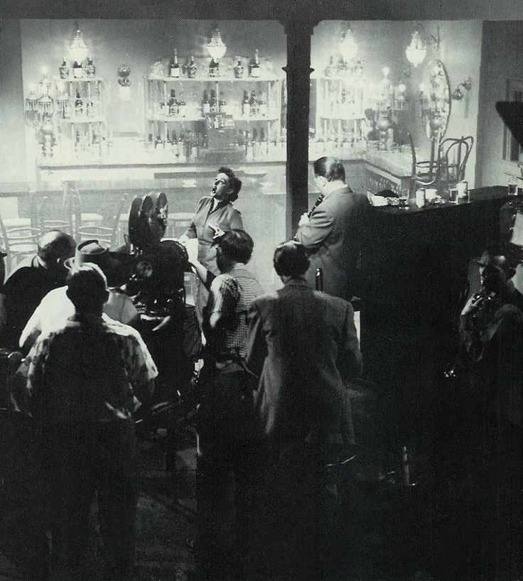 an old black and white photo of people in front of a bar with chandeliers