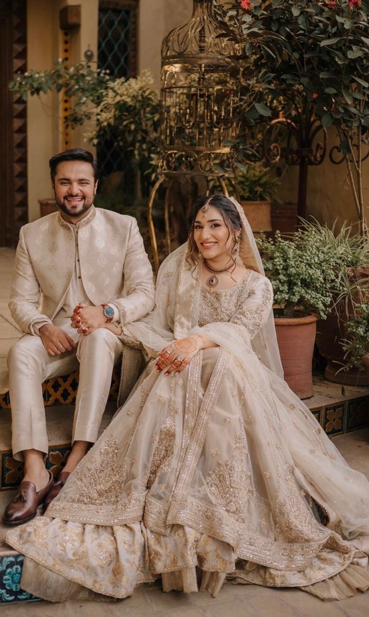 a man and woman sitting next to each other in formal wear, posing for the camera