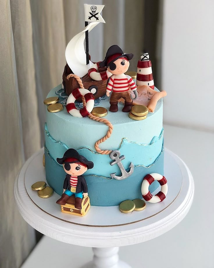 there is a blue cake with pirate figures on it and an anchor in the middle