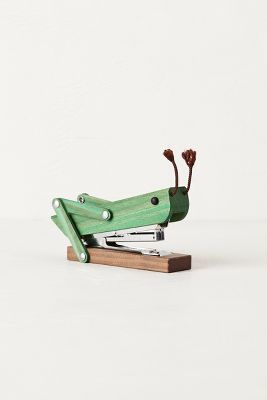 a green stapler sitting on top of a wooden block