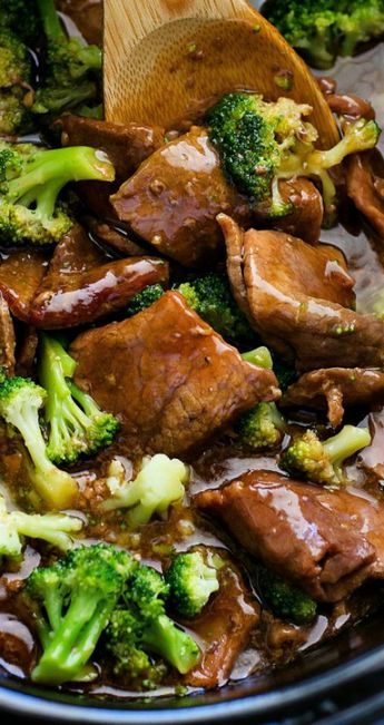 beef and broccoli stir fry in a slow cooker with a wooden spoon