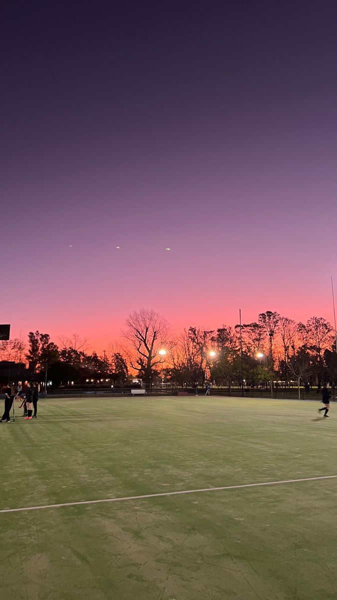 people are playing soccer on the field at sunset or dawn with bright lights in the distance