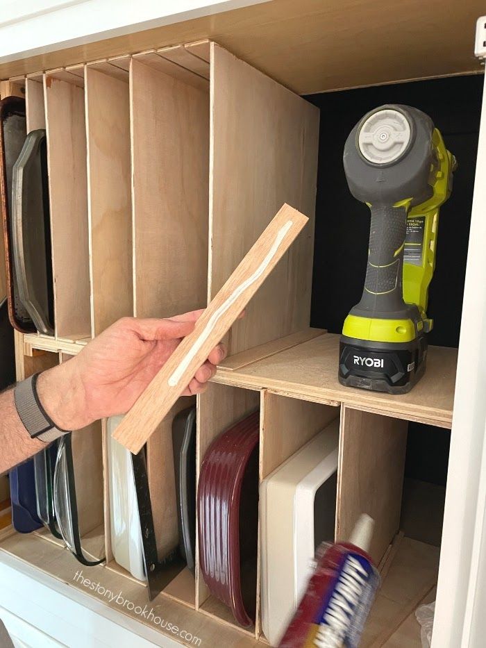 a person holding a piece of wood in a cabinet