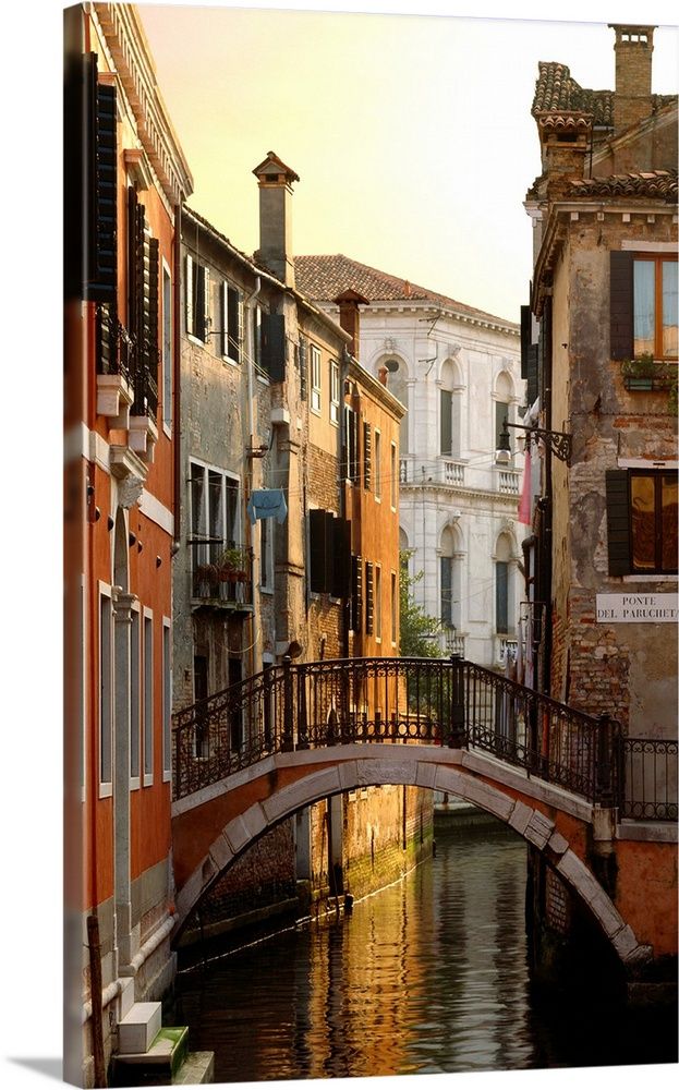 an old bridge over a canal in venice, italy with buildings lining both sides at sunset