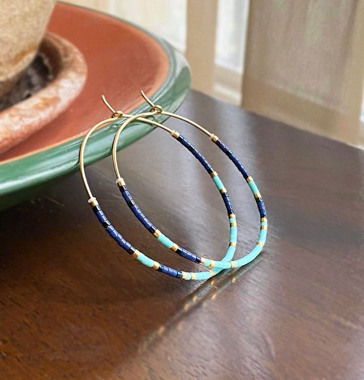 Dainty, delicate and lightweight hoop earrings featuring high quality tiny (2mm) Japanese Miyuki Glass Beads in turquoose and navy blue colors unto strong 20 gauge 14K Gold Filled OR .925 Sterling Silver wire (If you choose Sterling silver, the gold toned beads will be replaced with silver toned beads). To extend the life of the beads finish, I 'duracoat' them in my studio. Silicone bead 'bumpers' are added to keep the bead layout in place. You have an option to add French hooks. MATCHING NECKLACE: https://www.etsy.com/listing/1733713767/dainty-turquoise-blue-bead-necklace More HOOP EARRINGS, in my shop: https://www.etsy.com/shop/DorotaJewelry?ref=hdr_user_menu-shop&section_id=28150357 --- Please, keep in mind that the jewelry in the photographs looks larger than it does in person. I post Blue Hoop Earrings, Hoop Earrings Silver, Beaded Hoops, Silicone Beads, Matching Necklaces, Jewelry Earrings Hoops, Blue Beads, Elegant Gift, Earrings Silver