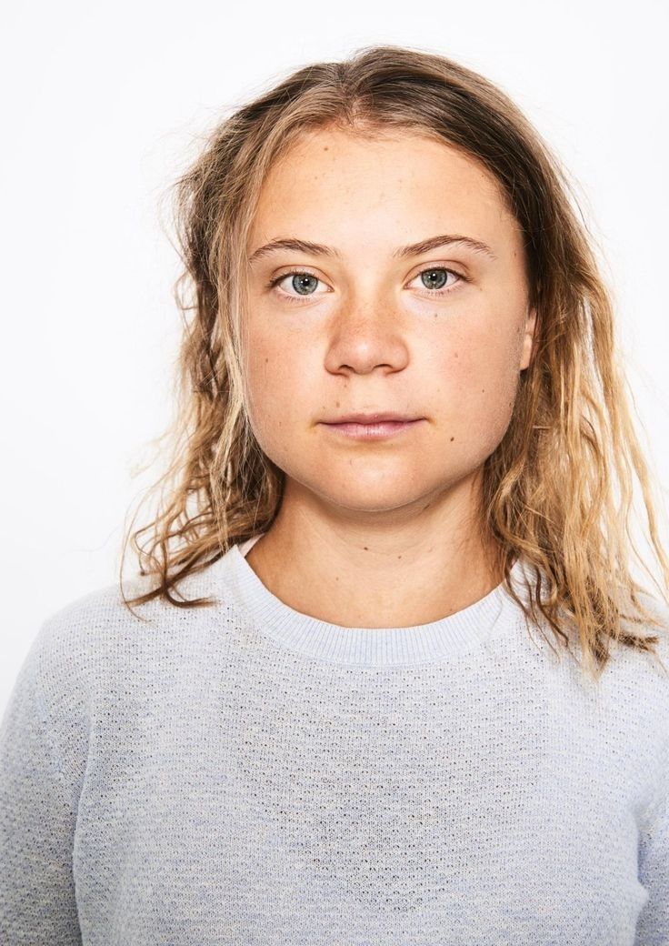 a woman with long hair and blue eyes looks at the camera while wearing a gray sweater