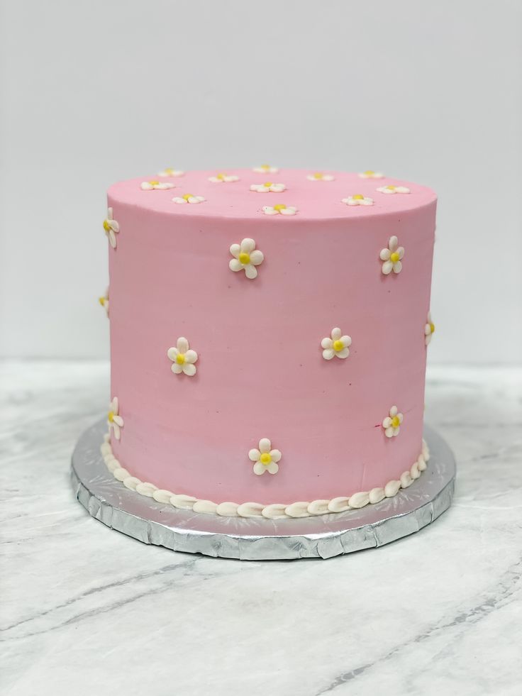 a pink cake with white and yellow flowers on it