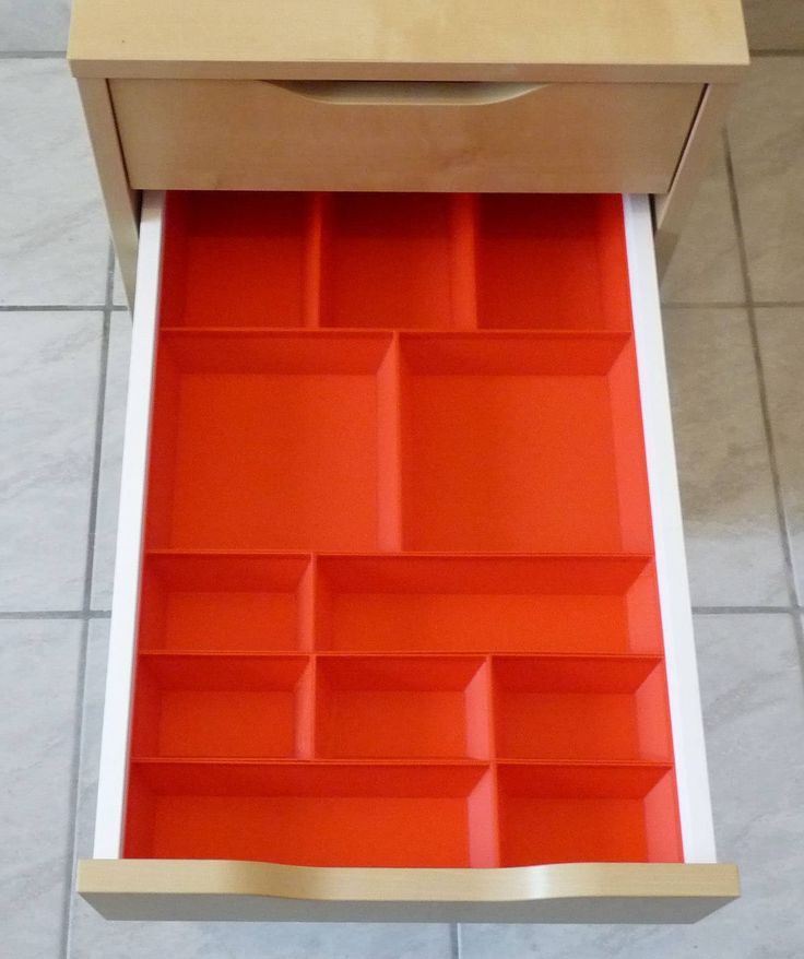 an orange drawer is open on the floor in front of a white counter top and tiled floor