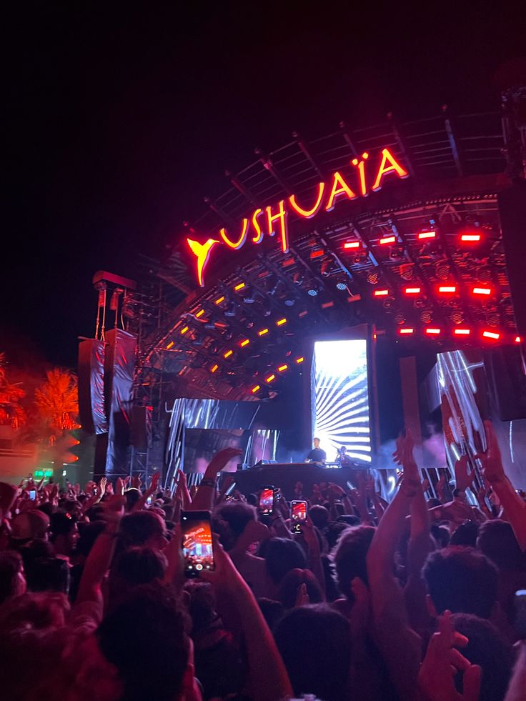 a large group of people at a concert with their cell phones up in the air