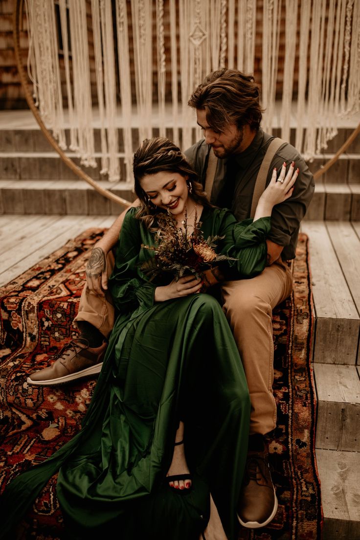 a man sitting next to a woman on top of a rug