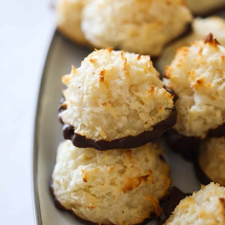 coconut cookies on a plate with chocolate drizzled on top and sprinkled with powdered sugar