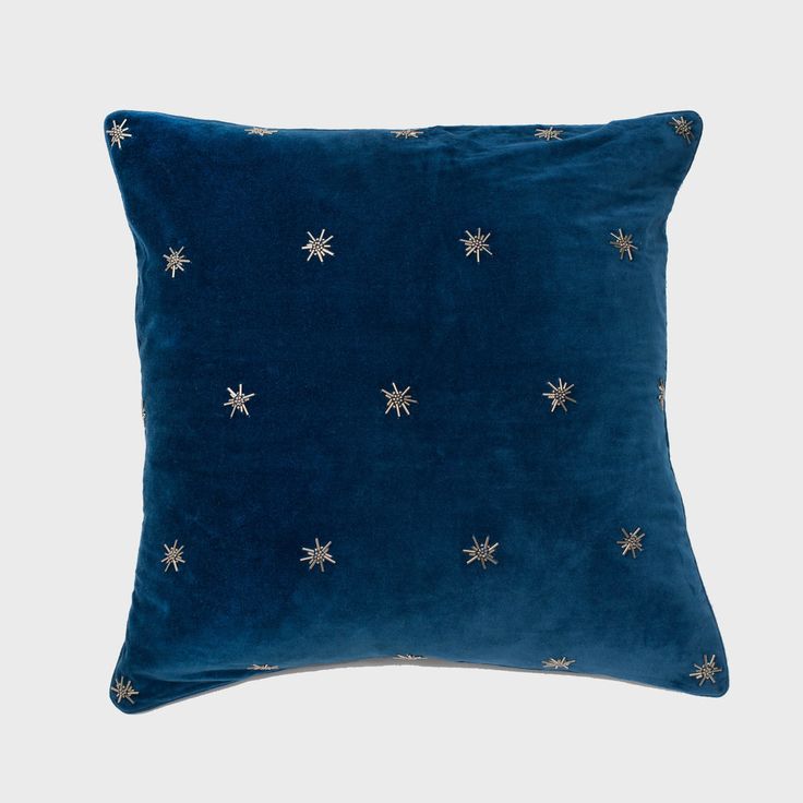 a blue velvet pillow with gold stars on the front and back, against a white background