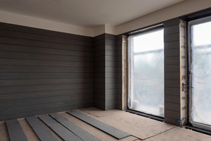 an empty room with several pieces of wood on the floor and two windows in the wall