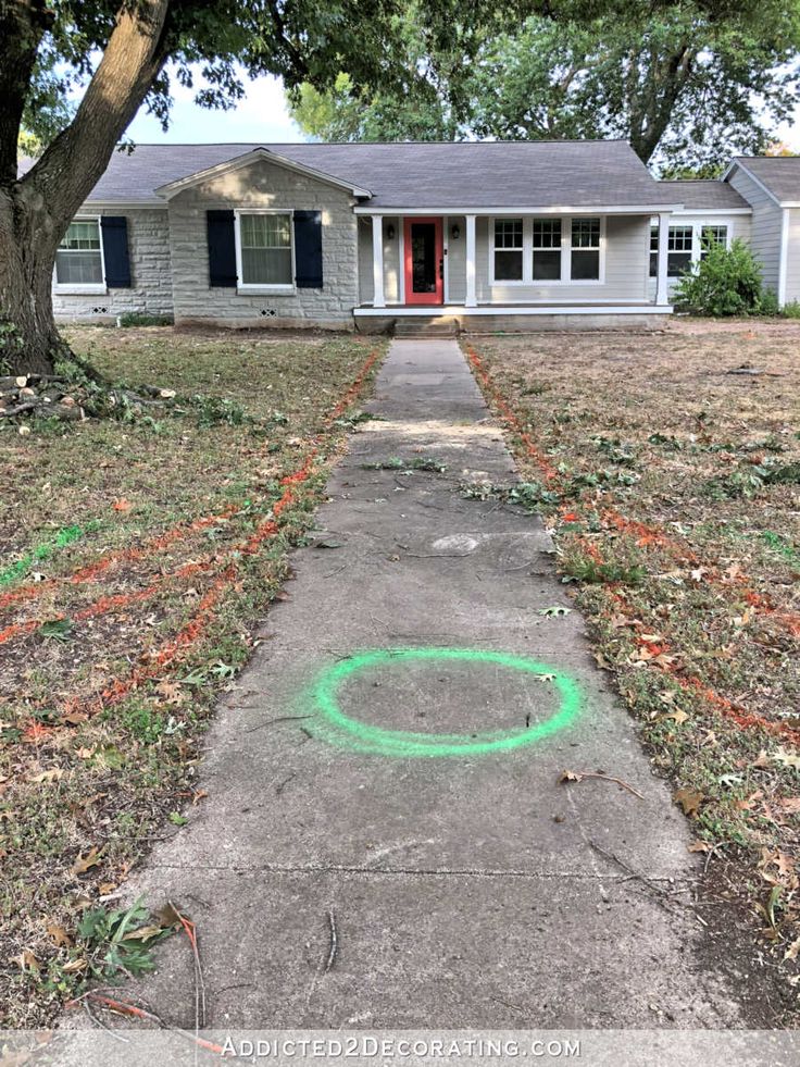 a sidewalk with green chalk on it in front of a gray house and red door