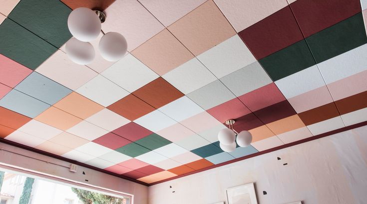 the ceiling is decorated with multicolored tiles and hanging light fixtures in an otherwise empty room