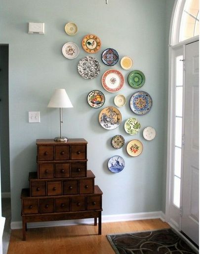 a wall with many plates on it and a lamp next to the dresser in front