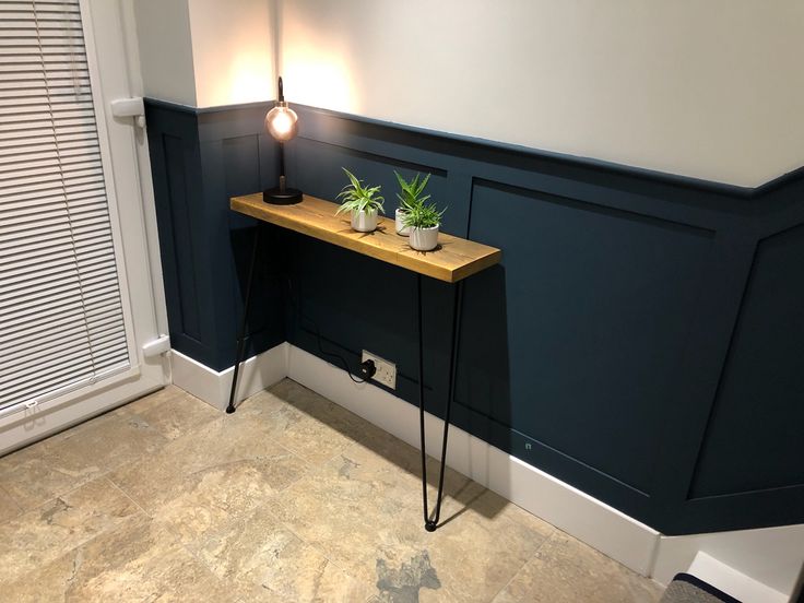 a small table with two plants on it next to a door and window sill