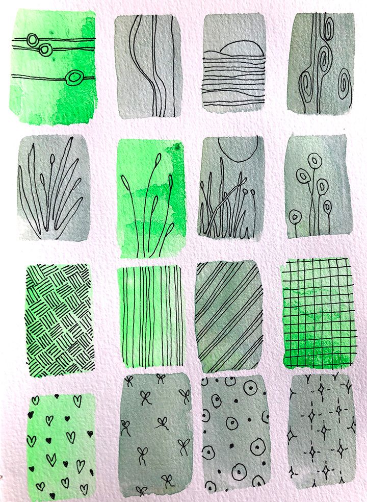 some green and black designs on a white paper with watercolor pencils in it