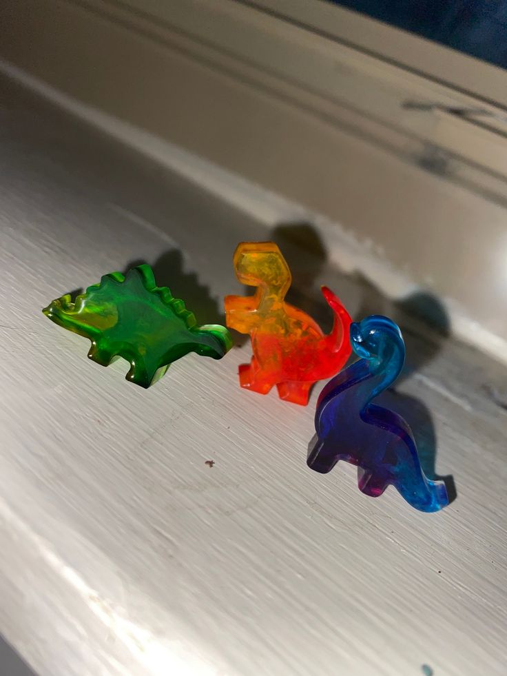 three small glass animals sitting on top of a white counter next to a window sill