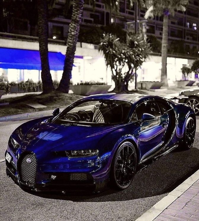 a blue bugatti is parked on the side of the road in front of some palm trees