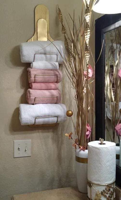 towels are stacked up on the wall in front of a mirror and toilet paper rolls