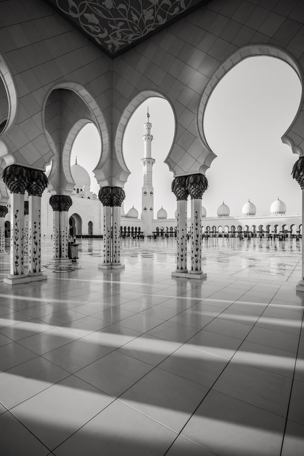 black and white photograph of the inside of a building with arches, pillars and minages