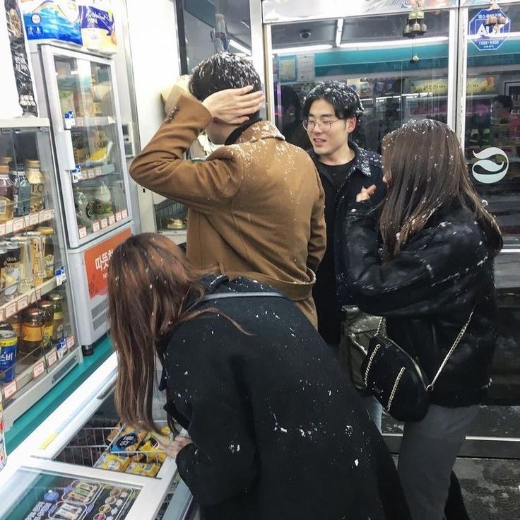 several people are standing in front of a vending machine and looking at the food