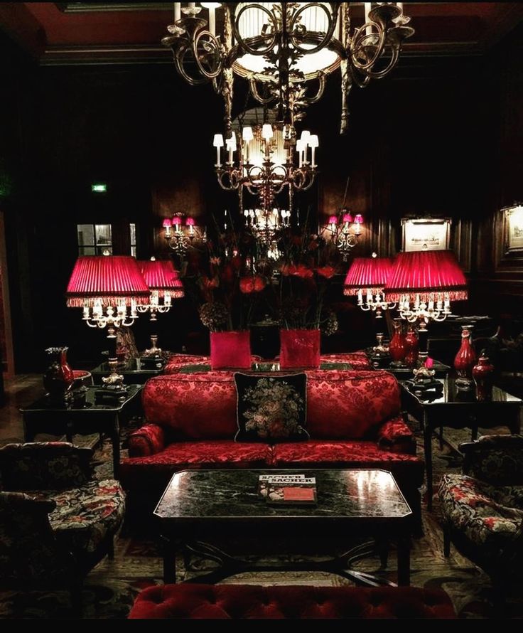 a living room filled with red couches and chandelier hanging from the ceiling