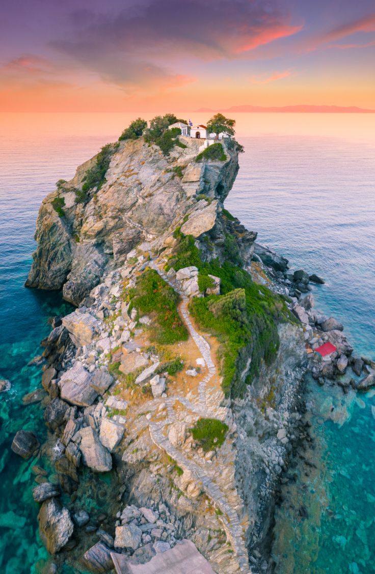 an island in the middle of the ocean with stairs leading up to it and a lighthouse on top