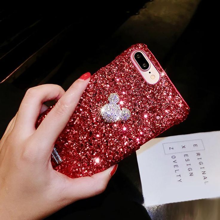 a hand holding a red glitter phone case with a heart on it's side