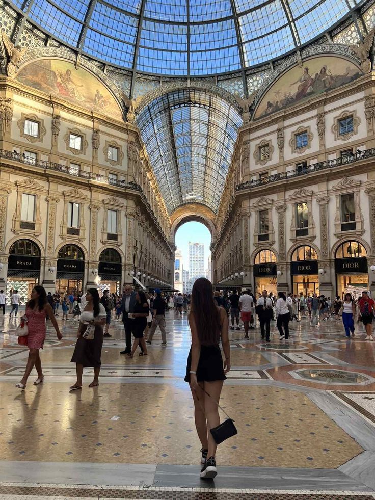 many people are walking around in an indoor shopping area with glass ceiling and high ceilings