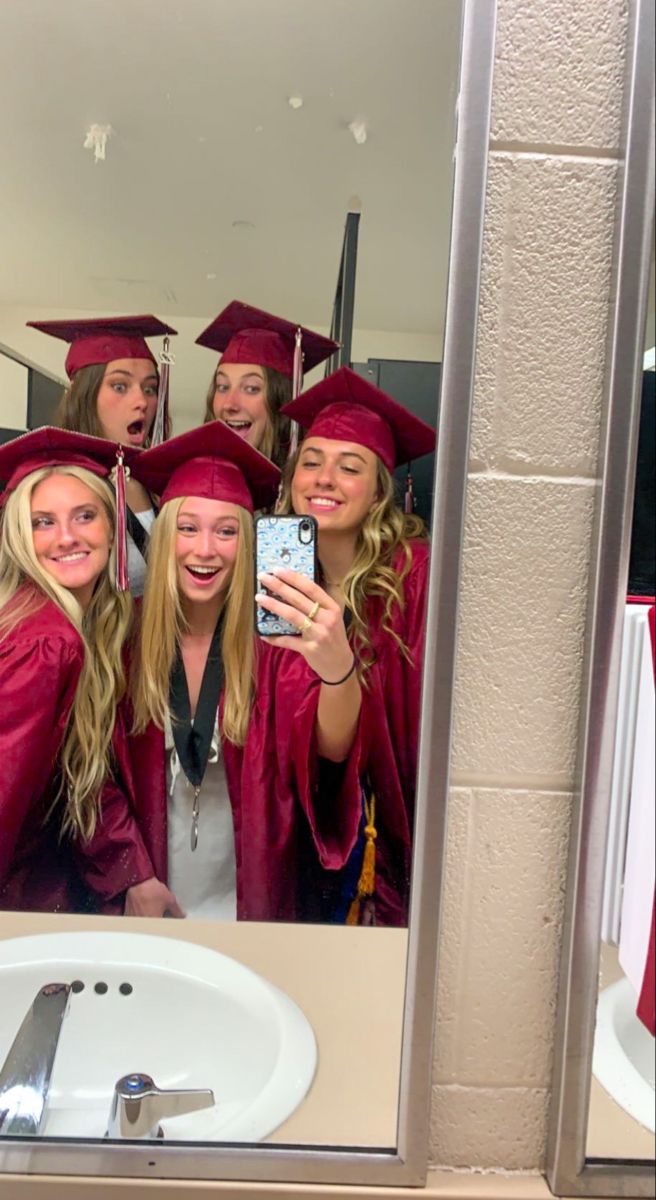 a group of women in graduation gowns taking a selfie