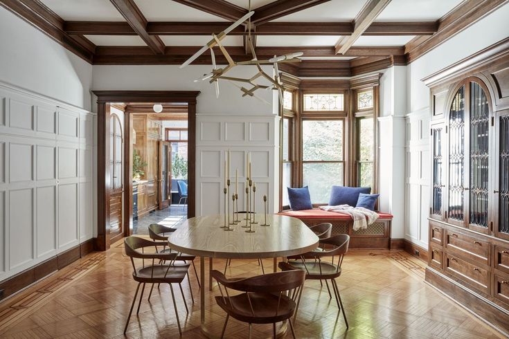 a large dining room with wood floors and white walls, along with wooden paneling