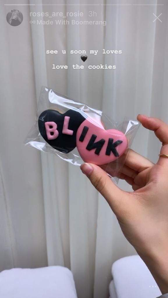 someone is holding up a pink and black cookie in their left hand with the word blkr on it