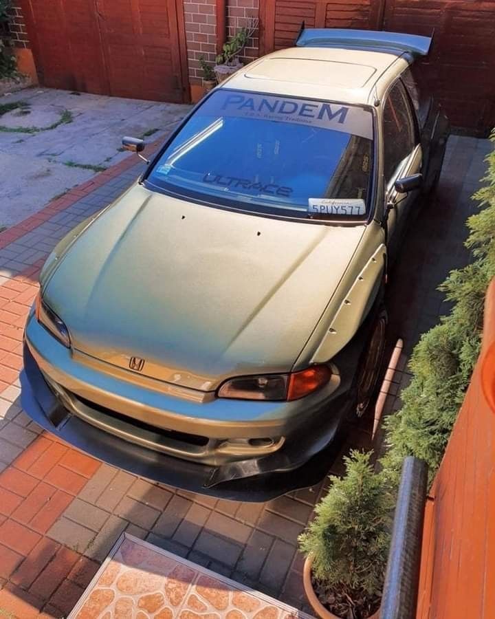 an older model honda accord is parked in front of a brick driveway and garage door