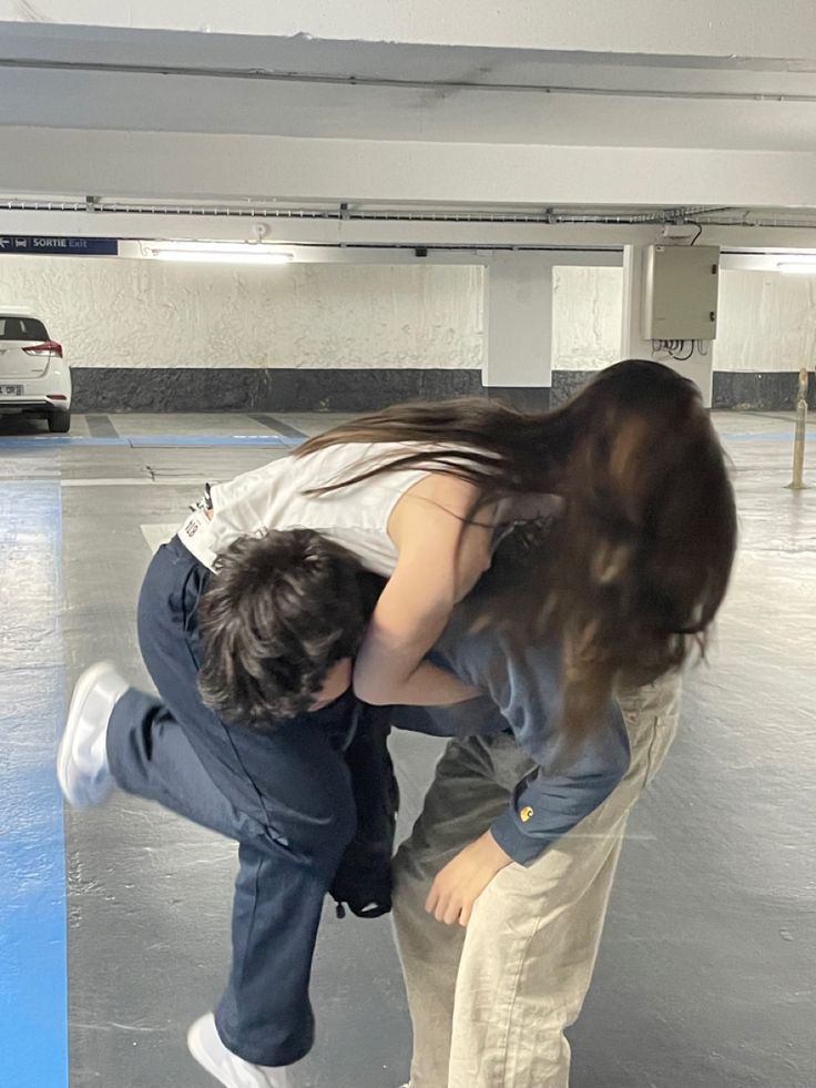 two people in an empty parking garage with one person holding the other's head